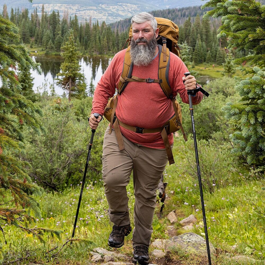 Man hiking in a forest with a backpack and walking sticks